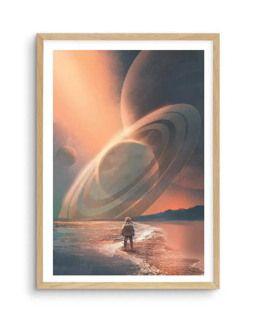 Art Print (illustration):
Science fiction art print featuring a solitary astronaut standing on a shoreline, gazing at a celestial landscape with multiple ringed planets and moons under an orange and teal sky, displayed in a natural oak frame with white border.