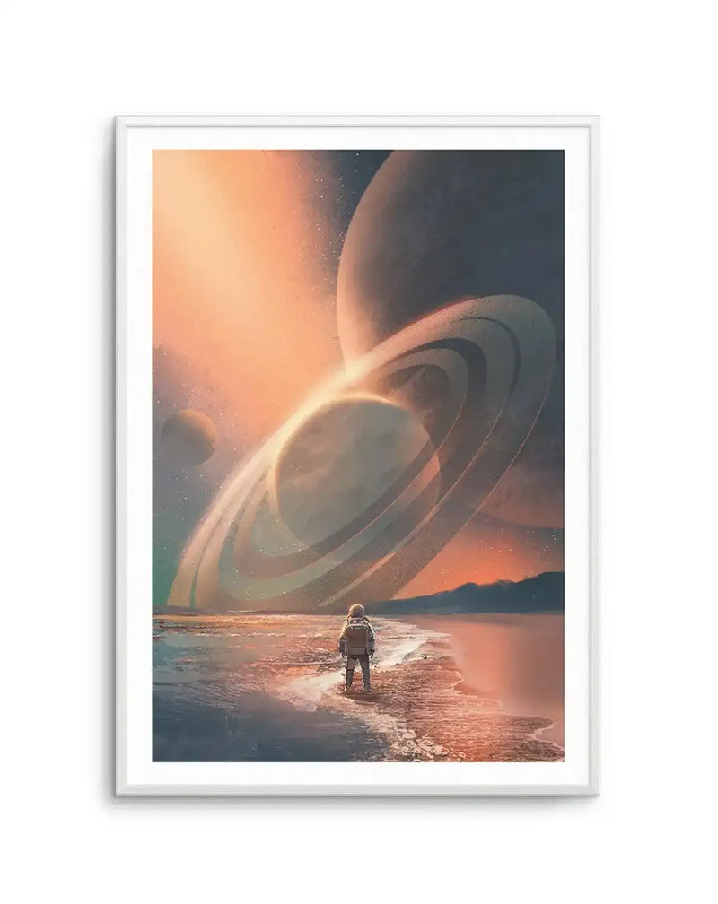 Science fiction art print featuring an astronaut standing on a beach, looking out at a vast alien landscape with multiple ringed planets and a glowing sun in the distance, displayed in a white frame with a white border. The sky is a gradient of warm orange and deep blue, filled with stars.