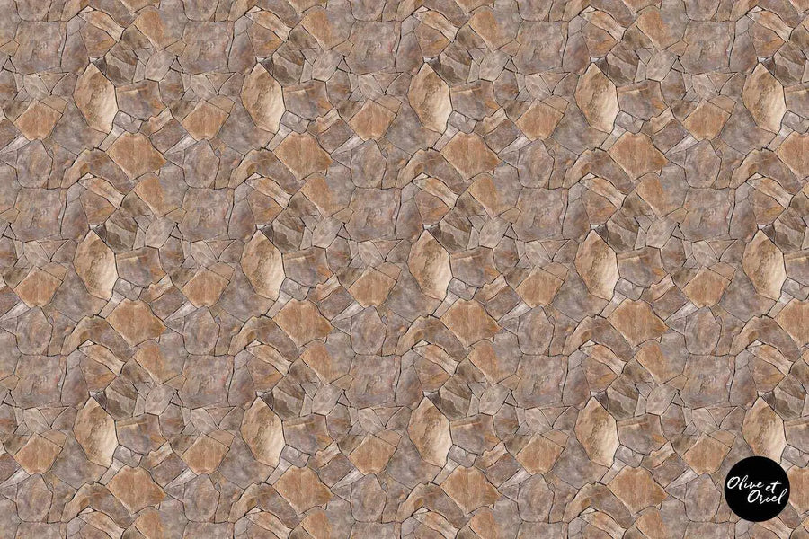 Peel and stick wallpaper featuring a repeating pattern of irregular, rough-hewn stones in varying shades of warm brown, grey, and beige, creating a natural, rustic texture.