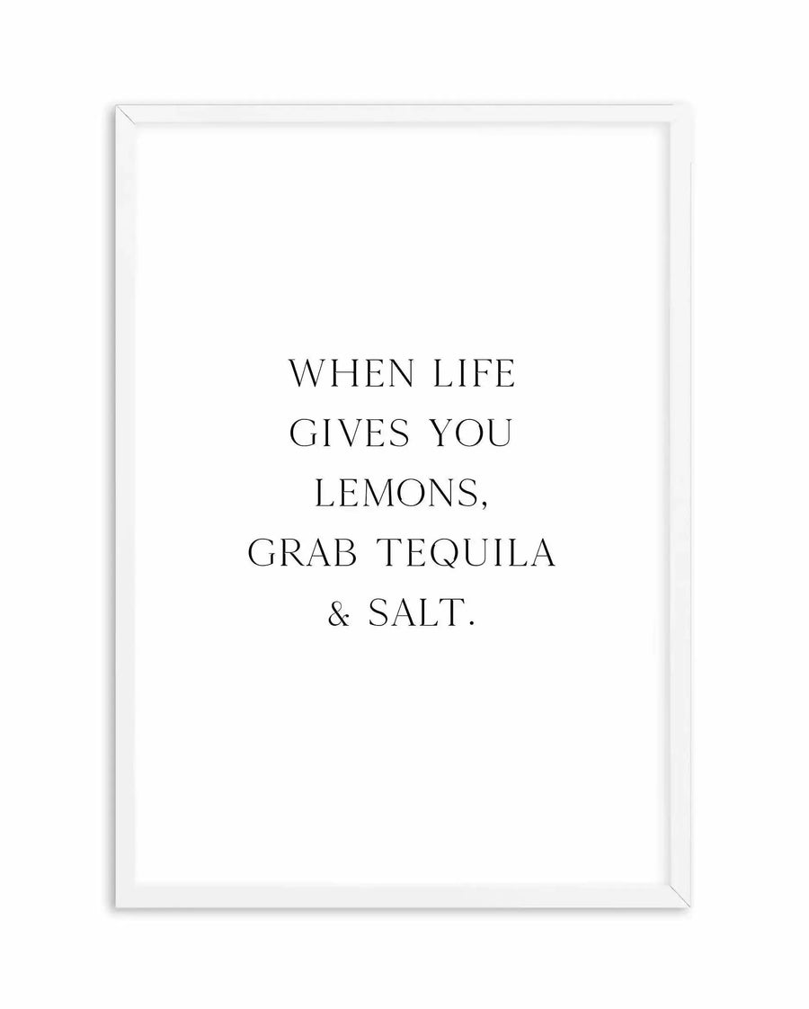 White framed art print featuring centered black serif text reading "WHEN LIFE GIVES YOU LEMONS, GRAB TEQUILA & SALT." displayed against a white background. The frame is white wood with a simple border, shown against a neutral white backdrop.