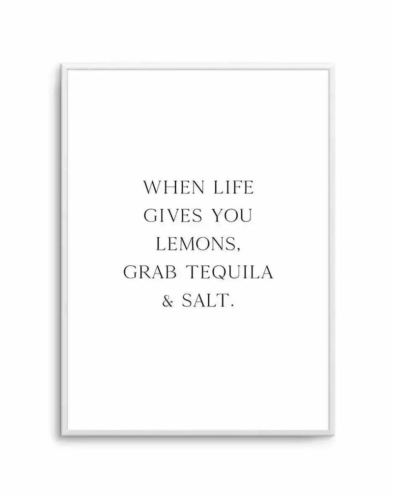 Framed art print with light gray frame displaying centered serif typography on white background. Black text reads "WHEN LIFE GIVES YOU LEMONS, GRAB TEQUILA & SALT." in all capitals across five lines. Minimalist design with ample white space surrounding the quote. Simple, clean aesthetic suitable for kitchen, bar, or home décor.