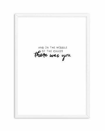 Art print featuring the hand-scripted quote "AND IN THE MIDDLE OF THE CHAOS there was you" in black, with the first line in a simple sans-serif font and the second line in a flowing script font, on a clean white background, displayed in a white frame with white border.