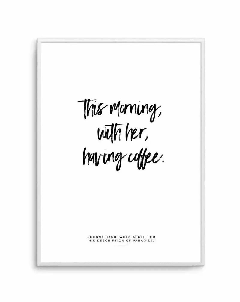 Art print in white frame featuring handwritten-style black text on white background. The main quote reads "This morning, with her, having coffee." in loose, flowing script centered on the page. Below in smaller serif font is the attribution "JOHNNY CASH, WHEN ASKED FOR HIS DESCRIPTION OF PARADISE." The print has a minimalist design with ample white space, creating a calm, intimate mood suitable for bedroom, kitchen, or living room display.