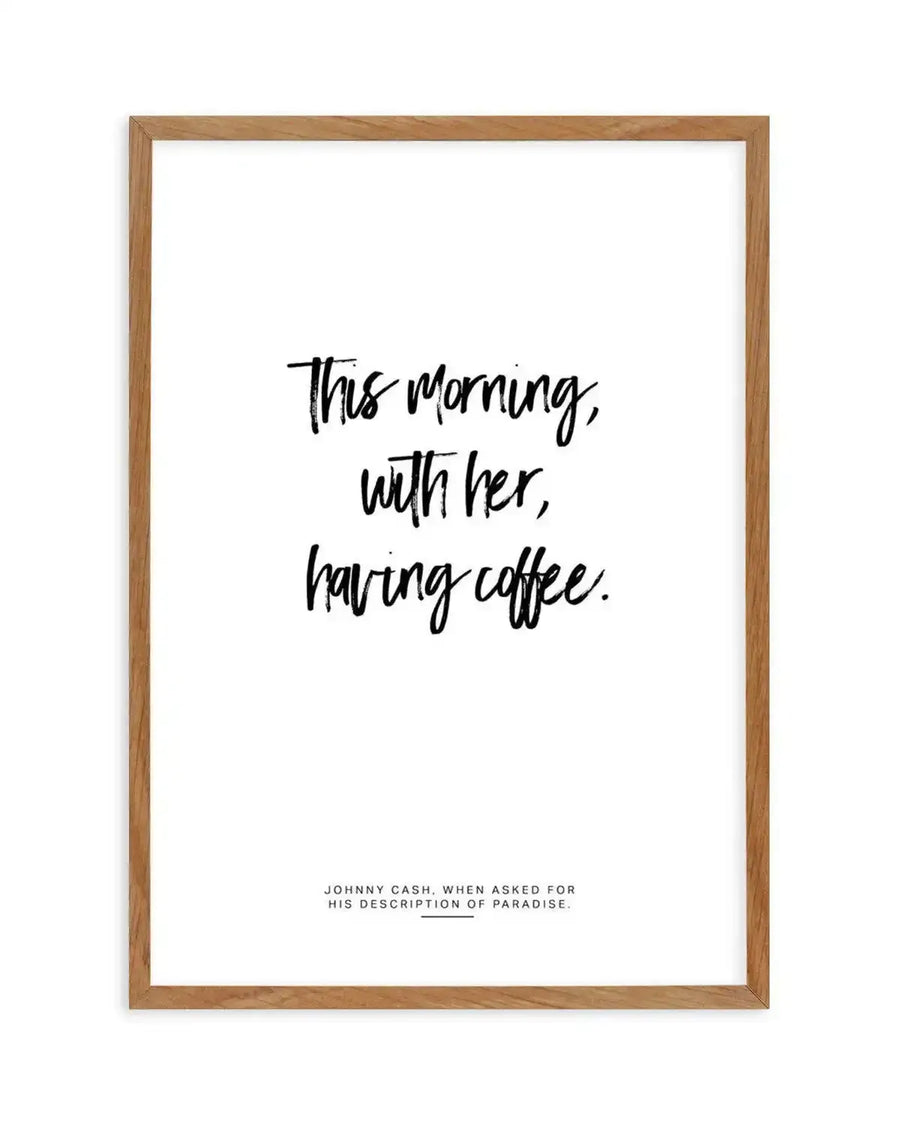 Art print featuring the handwritten quote "This morning, with her, having coffee." in black script on a crisp white background, displayed in a natural oak frame with white border. The text is centered and has a casual, expressive quality.