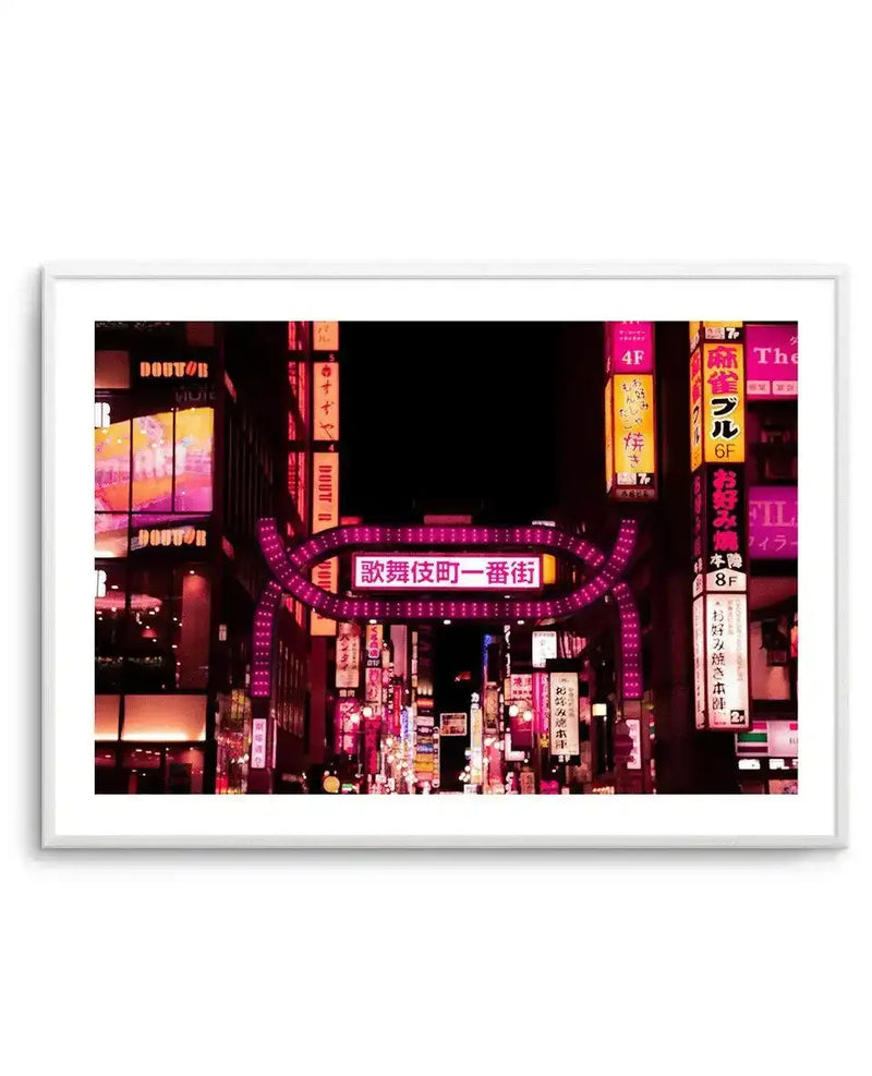 Framed photography art print of the Tokyo Red Light District at night, with a white frame and white border. The image captures a bustling street scene illuminated by vibrant neon signs in various shades of pink, red, and purple, with Japanese characters and English text on the signs. A prominent pink archway with "歌舞伎町一番街" (Kabukicho Ichibangai) in white text spans across the street, leading into a dense area of glowing storefronts and signs.