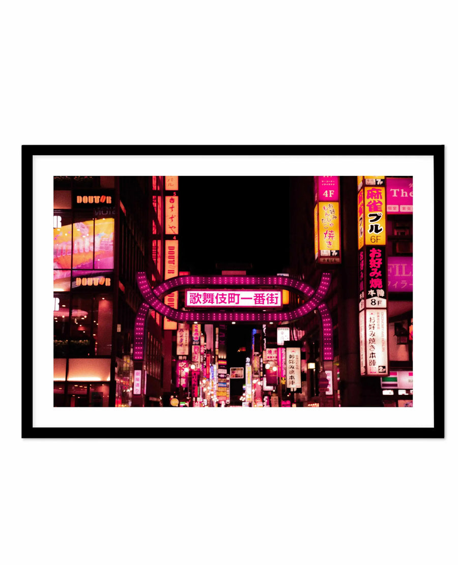 Framed photograph of a vibrant Tokyo street scene at night, dominated by neon signs in various shades of pink, magenta, and orange against a dark background, with a black frame and white border. The composition features a prominent illuminated archway with Japanese characters in the center, leading down a bustling street filled with glowing signs and reflections.