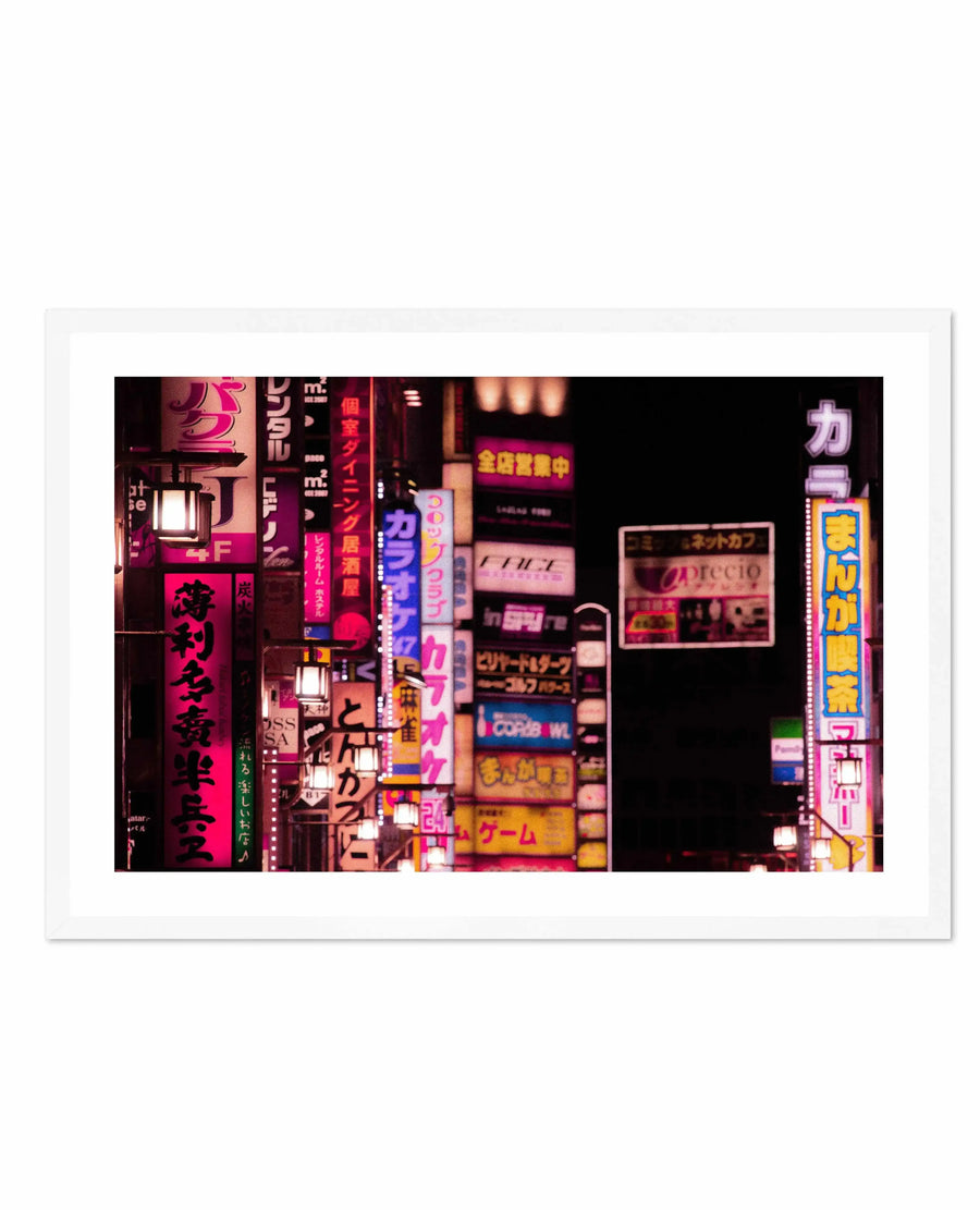 Framed photography art print depicting a vibrant night scene in Tokyo's Red Light District, with a natural wood frame and white border. The composition features numerous neon signs in various shades of pink, red, blue, and yellow, with Japanese characters and some English text, illuminating a dark street. Traditional lanterns with warm glows are interspersed among the signs, creating a bustling and energetic atmosphere.