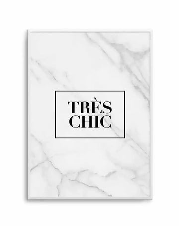 Art print featuring the text "TRÈS CHIC" in bold black serif capital letters centered within a black rectangular border on a white marble-textured background. The marble has subtle gray veining throughout. The print is mounted in a silver-gray frame with a white border. The overall composition has a minimalist, sophisticated aesthetic with high contrast between the black text and white background.