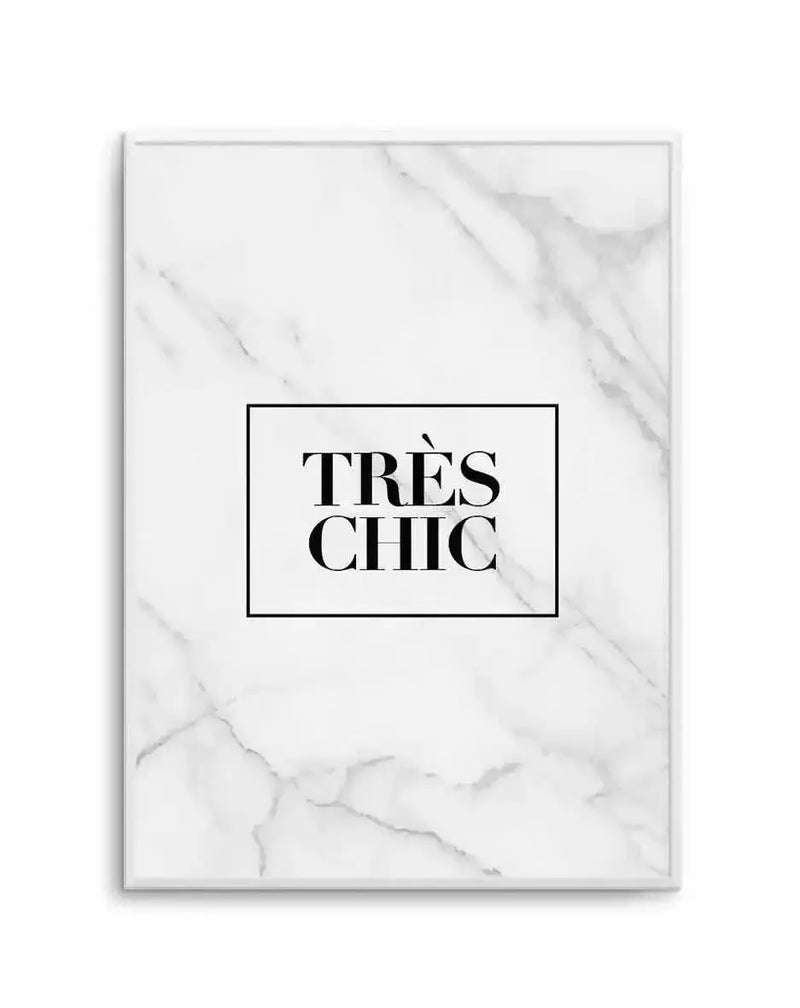 Art print featuring the text "TRÈS CHIC" in bold black serif capital letters centered within a black rectangular border on a white marble-textured background. The marble has subtle gray veining throughout. The print is mounted in a silver-gray frame with a white border. The overall composition has a minimalist, sophisticated aesthetic with high contrast between the black text and white background.