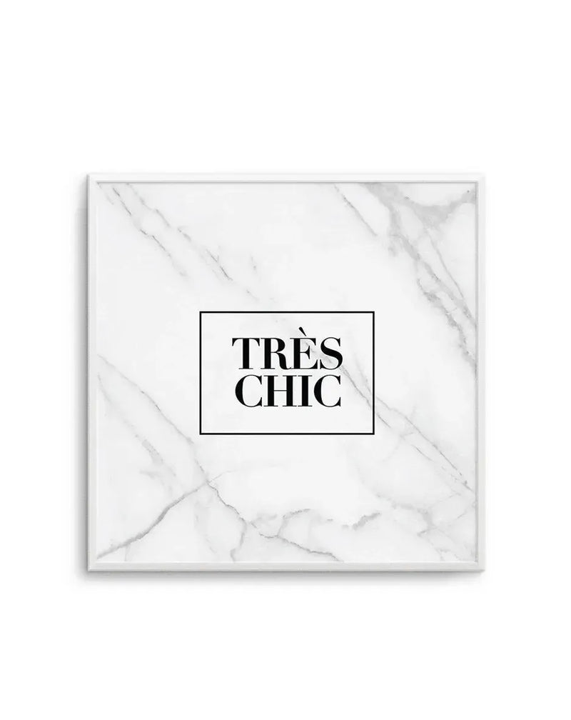 Framed art print on white marble-textured background with gray veining throughout. The print features the text "TRÈS CHIC" in bold black serif font, centered within a thin black rectangular border. The artwork is displayed in a silver-toned frame with a white border, mounted against a light background.