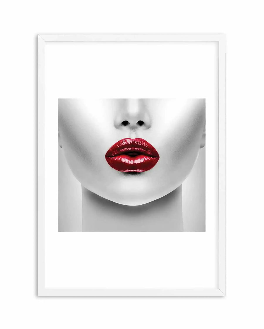 Art print in white frame featuring close-up black and white portrait of lower half of face with bold deep red lipstick, pale skin, and subtle nose detail. High-contrast minimalist photography style with soft lighting. White border surrounding the image within the frame.