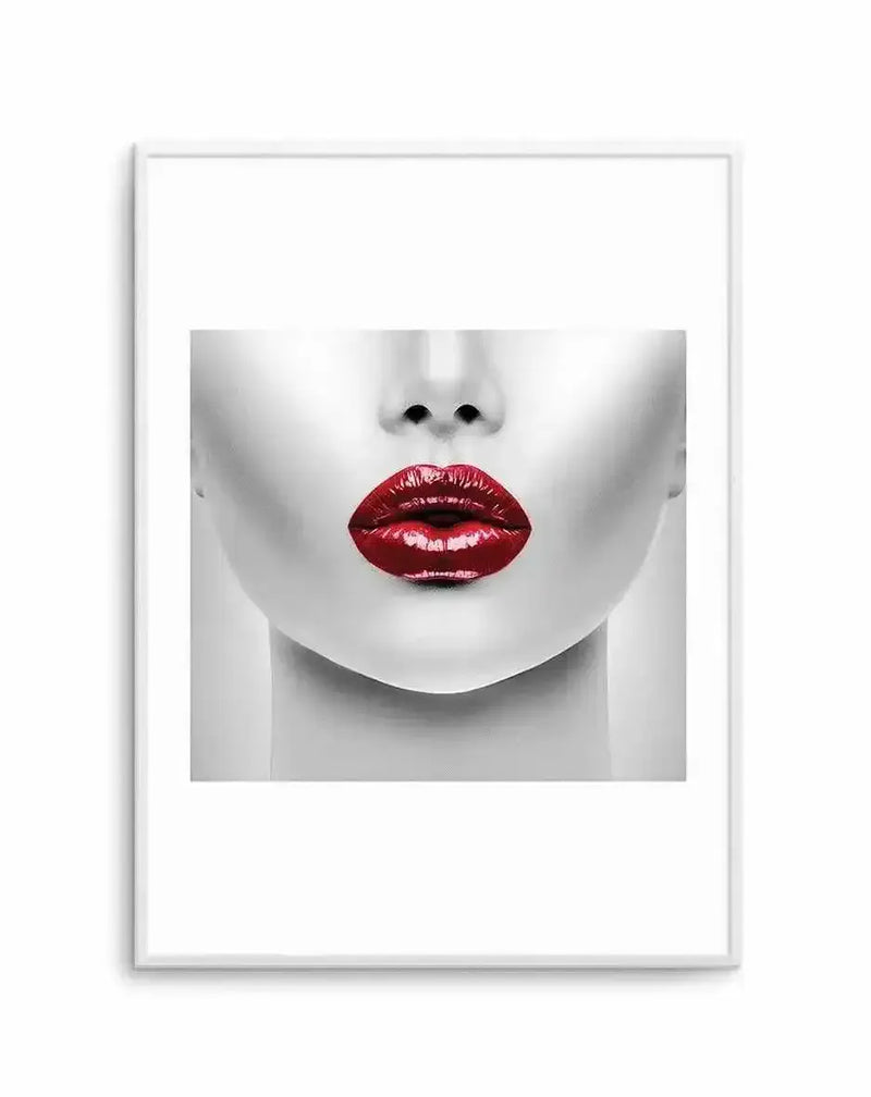 Framed art print featuring a minimalist portrait of a face in grayscale with striking deep crimson red lips. The face is shown from nose to chin against a white background, with subtle shading and contours. The artwork is displayed in a white frame with a white border, creating a clean, gallery-like presentation. The high-contrast composition emphasizes the bold lip color as the focal point against the neutral monochromatic tones of the face and background.