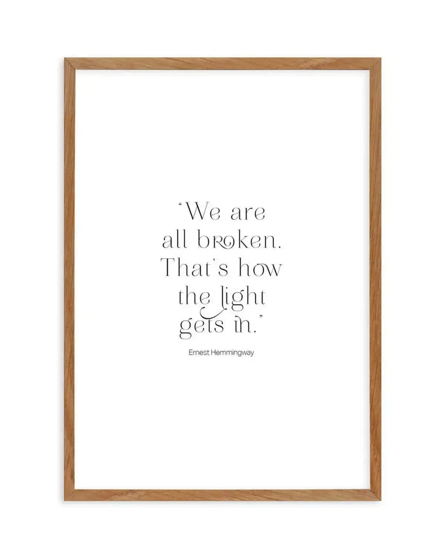 Art print featuring the quote "We are all broken. That's how the light gets in." in elegant black serif font on a crisp white background, displayed in a natural oak frame with white border.