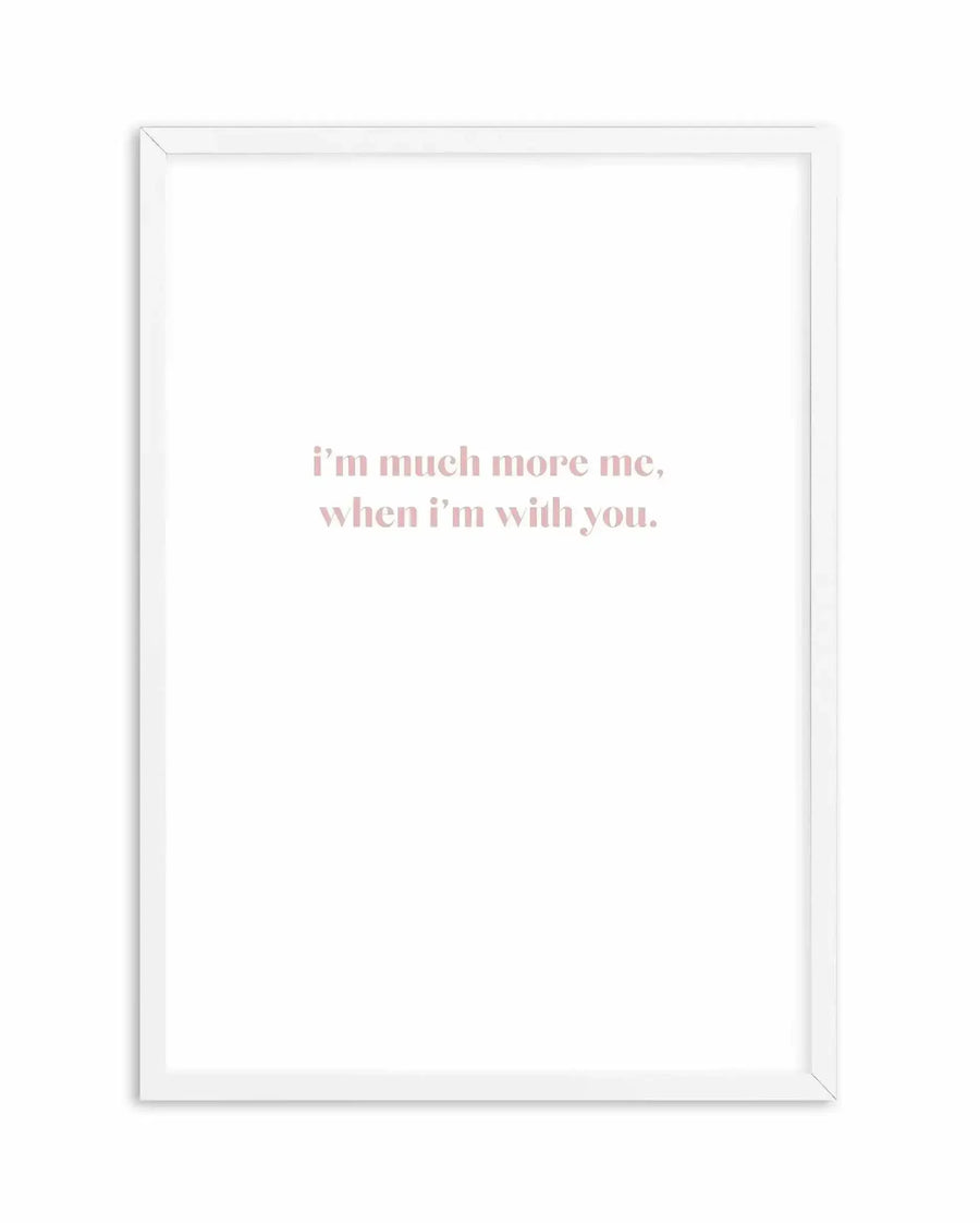White framed art print featuring centered text in dusty rose pink that reads "i'm much more me, when i'm with you." on a white background. The frame is simple white wood with a clean, minimalist aesthetic.