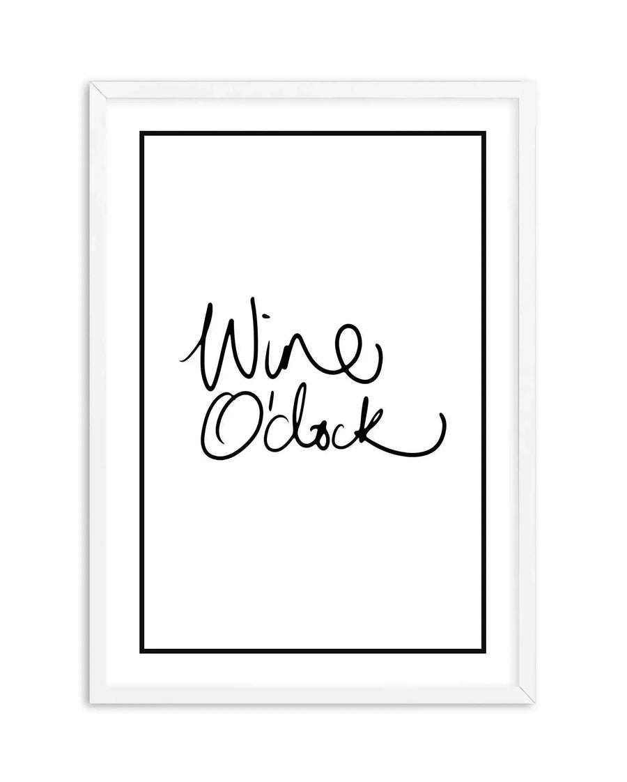 A framed art print featuring handwritten script text reading "Wine O'Clock" in black ink on a white background. The artwork is displayed in a white wooden frame with a white border around the black-bordered design. The lettering has a casual, flowing cursive style with decorative flourishes on the letters.