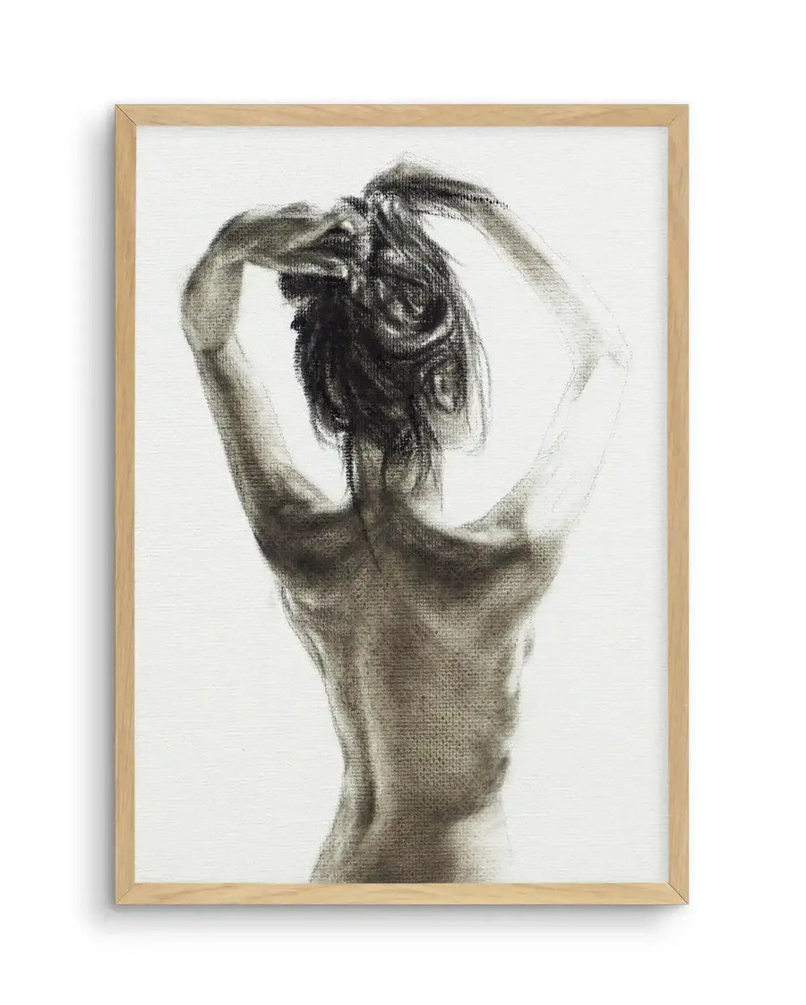 Charcoal art print featuring a woman viewed from the back, with her arms raised above her head as if tying up her hair. The drawing captures the musculature of her back and arms with visible charcoal strokes, creating a textured, expressive quality against a white background. The print is displayed in a natural oak frame with a white border.
