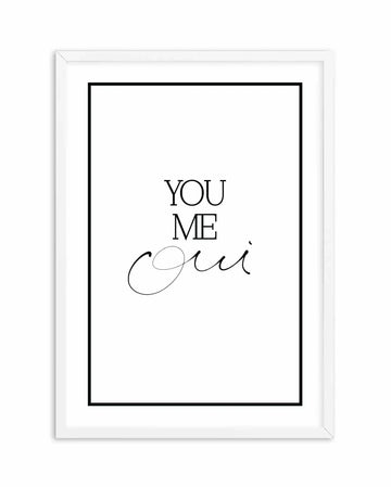 White framed art print with black border containing hand-scripted typography. Text reads "YOU" and "ME" in clean sans-serif font, followed by "oui" in elegant, flowing cursive script. Minimalist design on white background. White wood frame with simple molding.